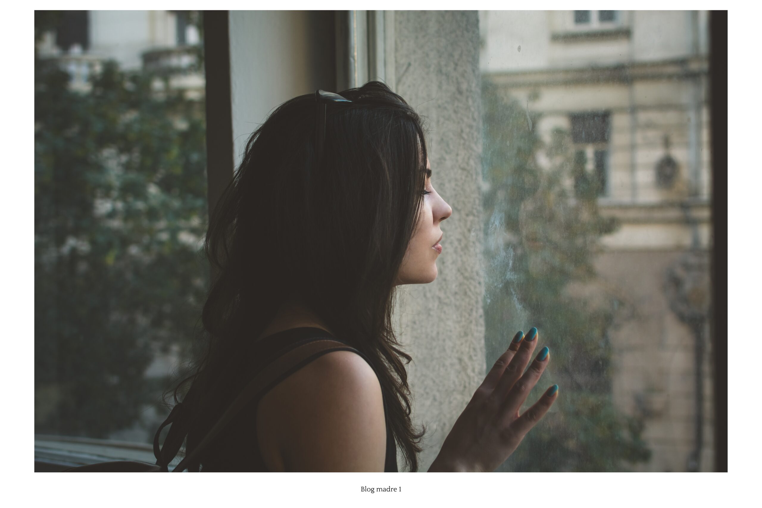 terapia, Mujer mirando por la ventana con expresión reflexiva, representando el ciclo del autosabotaje.